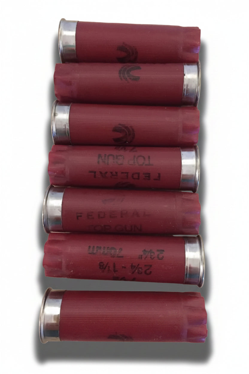 7 dark red Federal Top Gun 12 gauge shotgun shells lying in a row with silver bases