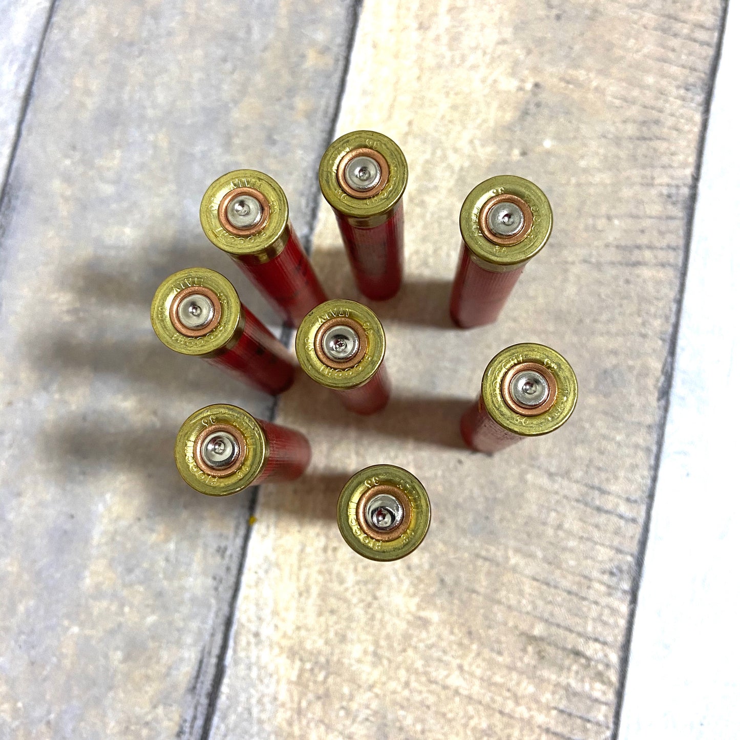 Empty red 410 bore shotgun shells with brass bases viewed from above showing headstamps on a wood deck