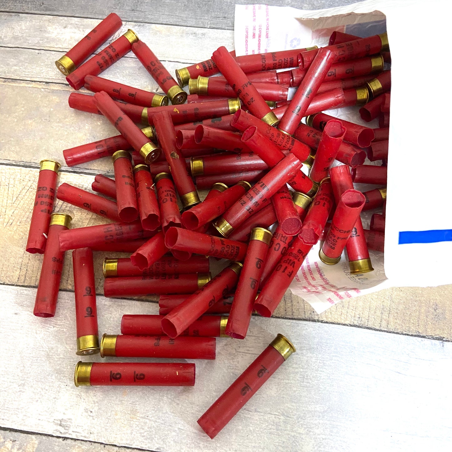 Large pile of empty red 410 bore shotgun shells with brass bases spilling out of a cardboard shipping box