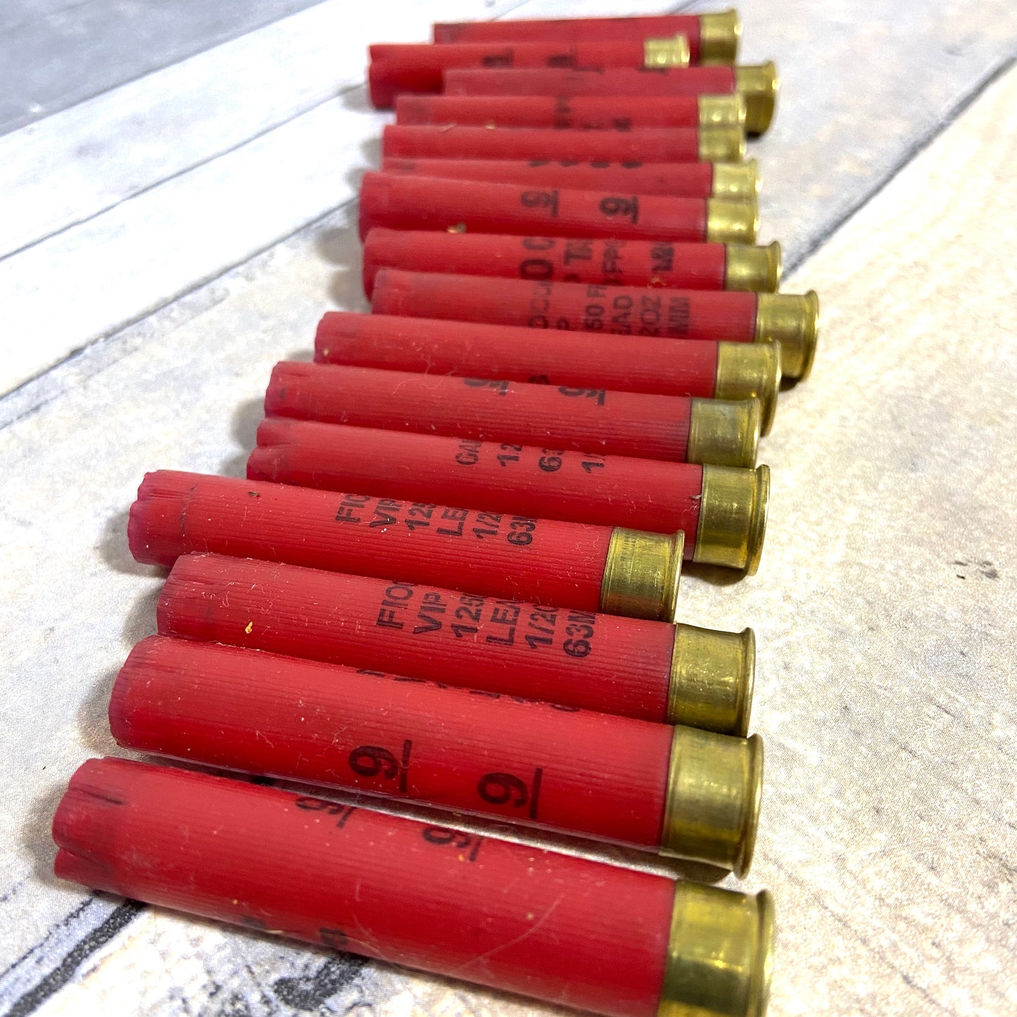 Row of empty red 410 bore shotgun shells with brass bases lying on a wood deck