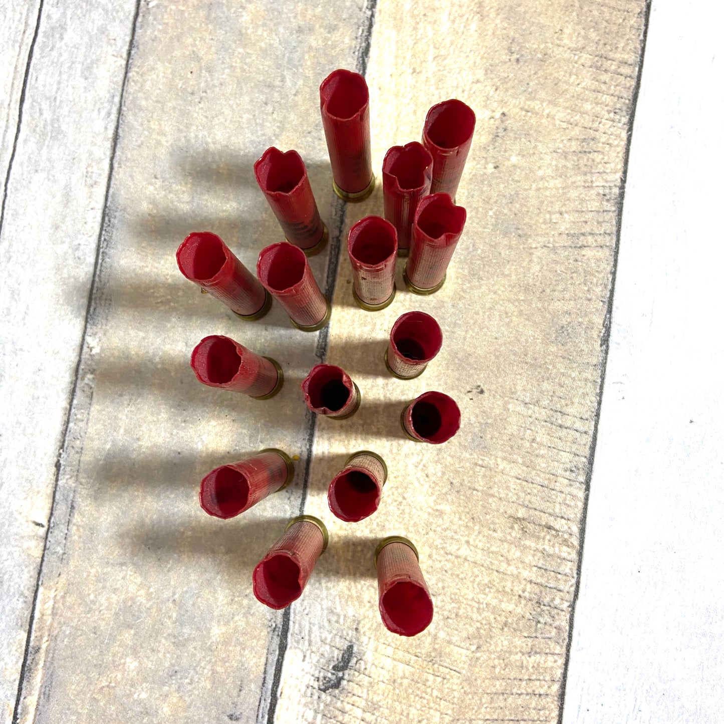 Empty red 410 bore shotgun shells with brass bases viewed from above on a wood deck