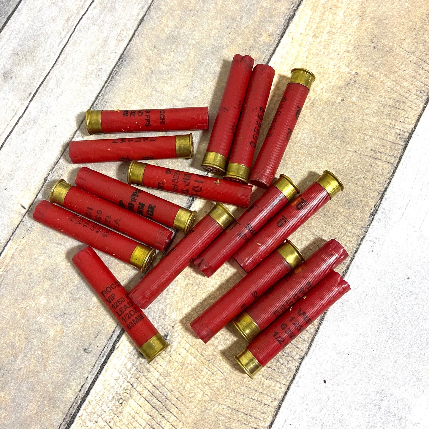 Pile of empty red 410 bore shotgun shells with brass bases on a wood deck