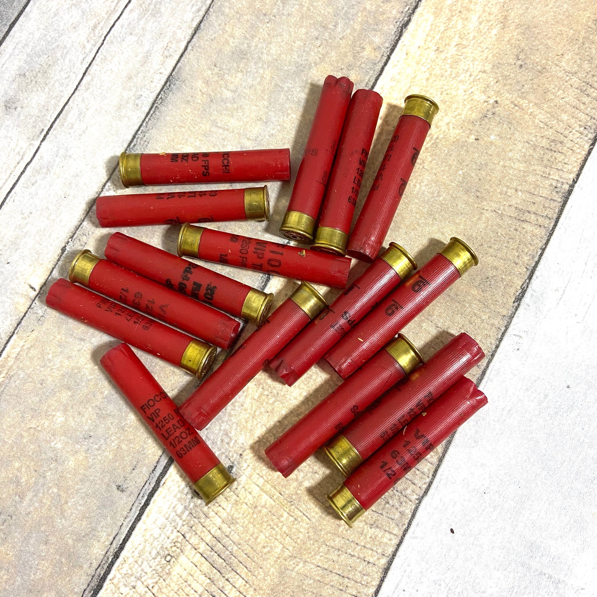 Pile of empty red 410 bore shotgun shells with brass bases on a wood deck