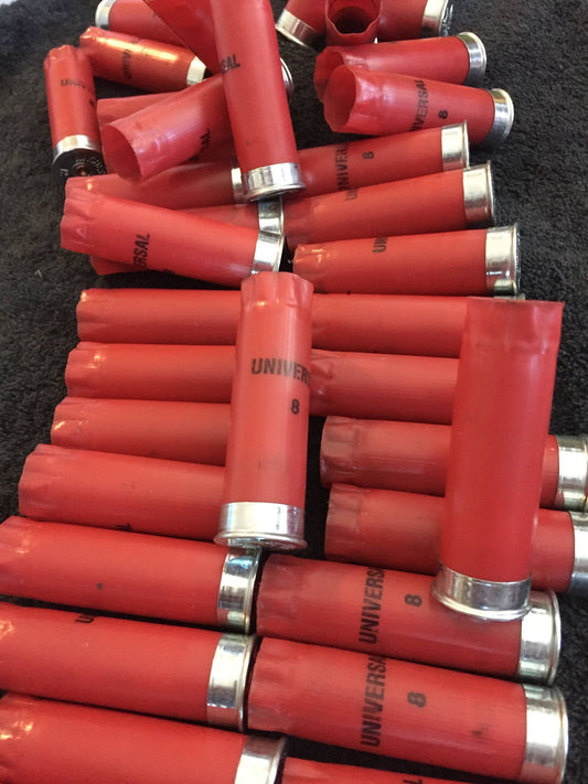 Bulk pile of red Winchester Universal shotgun shells with silver metal bases stacked on a dark background.