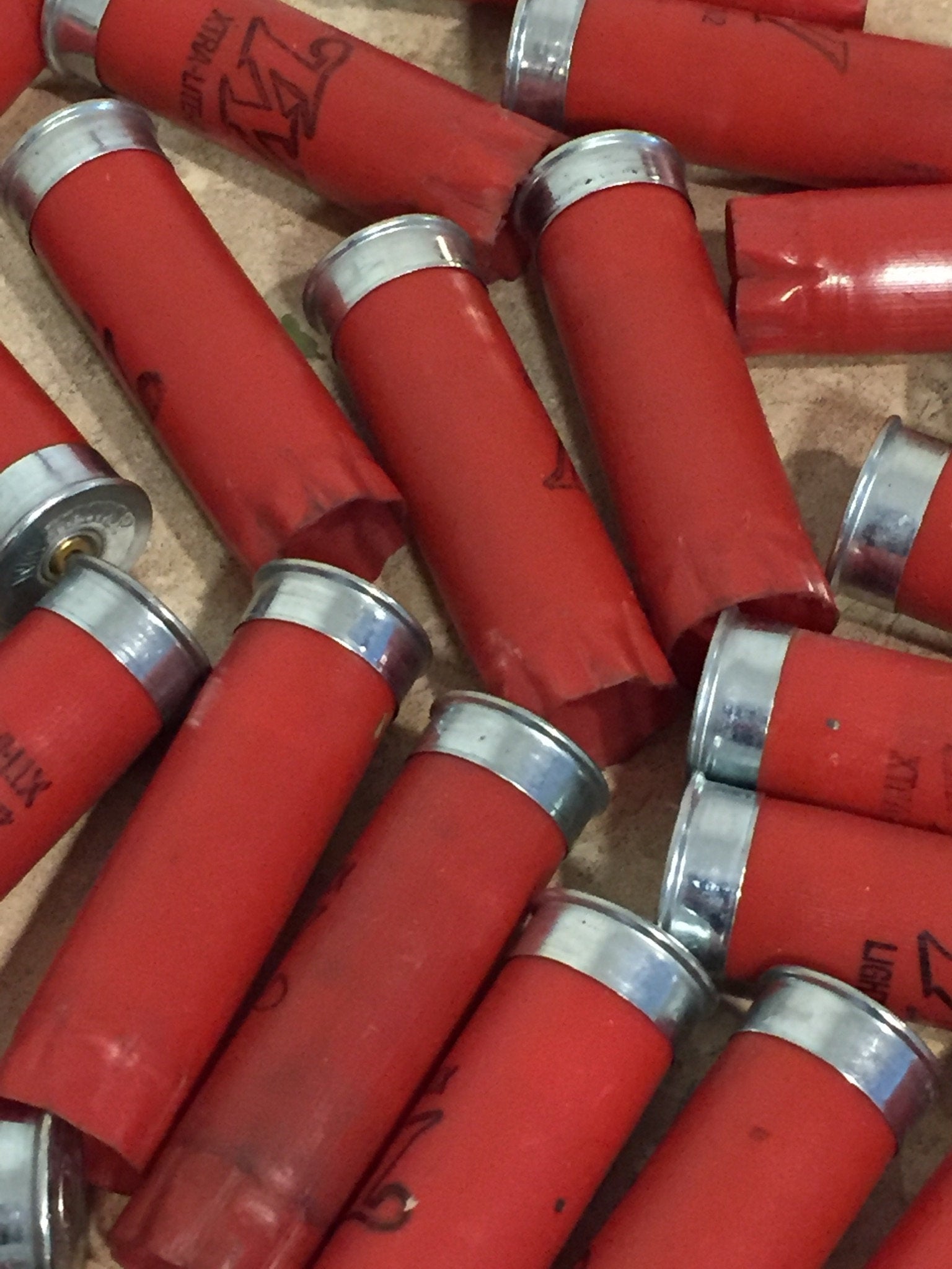 A pile of red Winchester shotgun shells with silver bottoms lying together