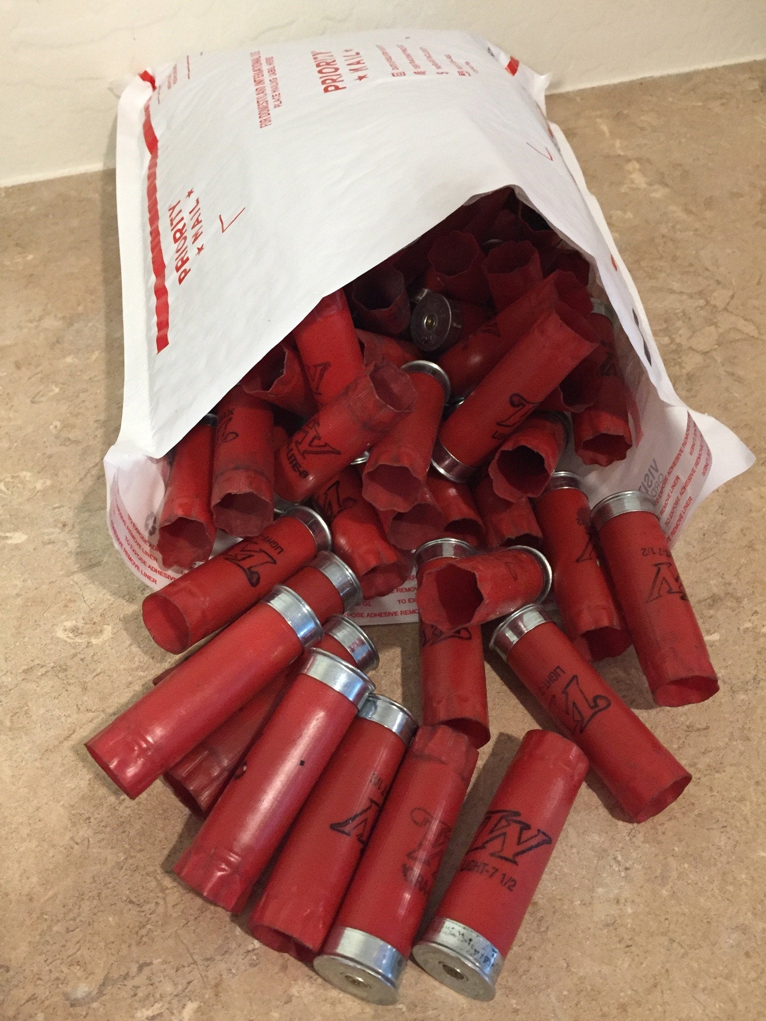 A pile of red Winchester shotgun shells spilling out of a Priority Mail shipping bag