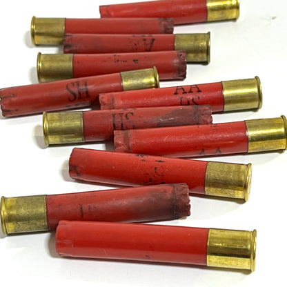 Red Winchester AA 410 bore shotgun shell hulls marked AA and HS scattered on a white surface