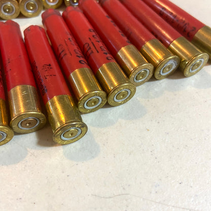 Rows of red Winchester AA 410 bore shotgun shell hulls next to a ruler for scale