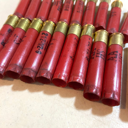 Red Winchester AA 410 bore shotgun shell hulls in a row with open ends bundled together