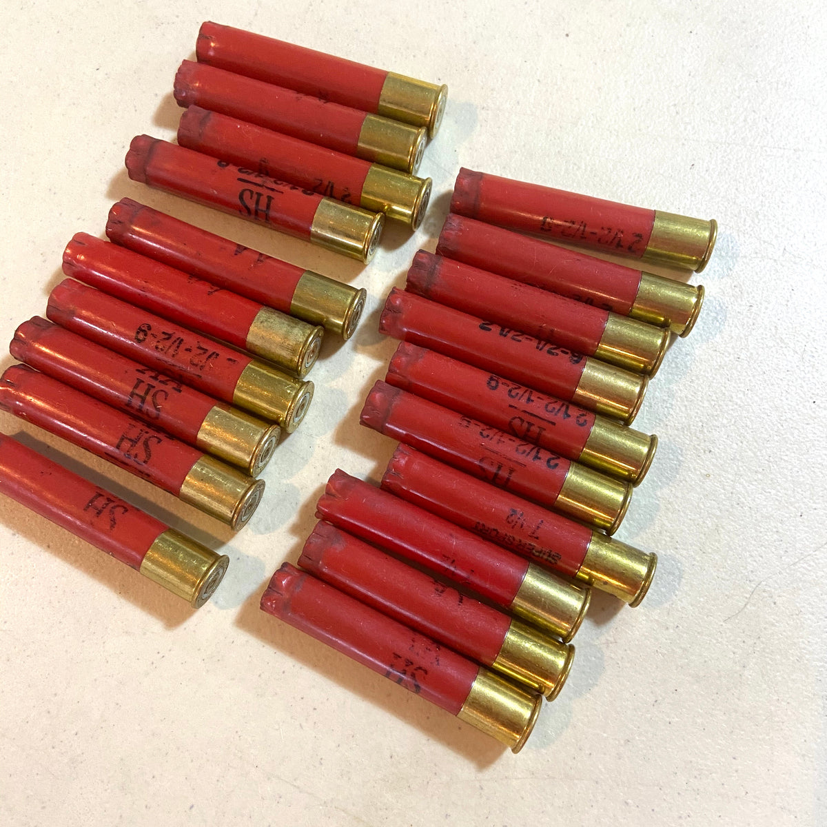 Red Winchester AA 410 bore shotgun shell hulls arranged in two rows on a white surface