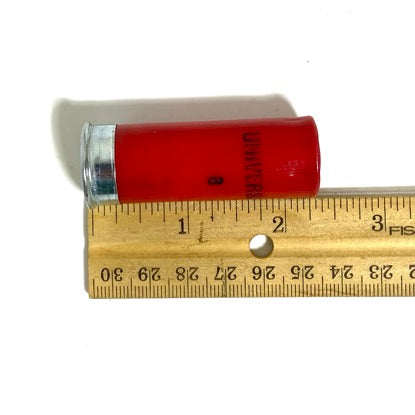 Four red 12 gauge Winchester dummy rounds stacked next to a wooden ruler demonstrating 2 3/4 inch shell length.