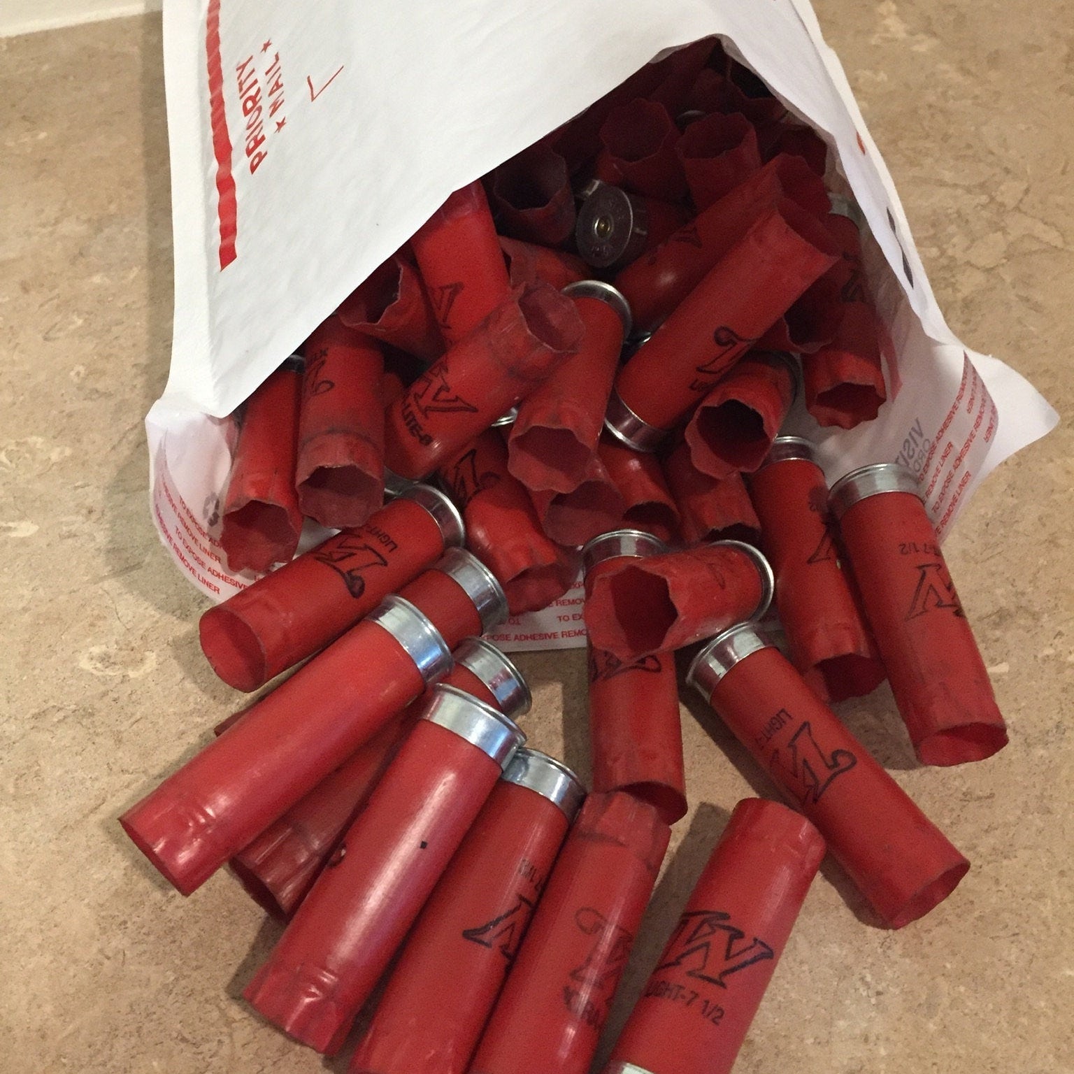 Priority Mail shipping bag spilling out bulk loose-packed red Winchester shotgun shells