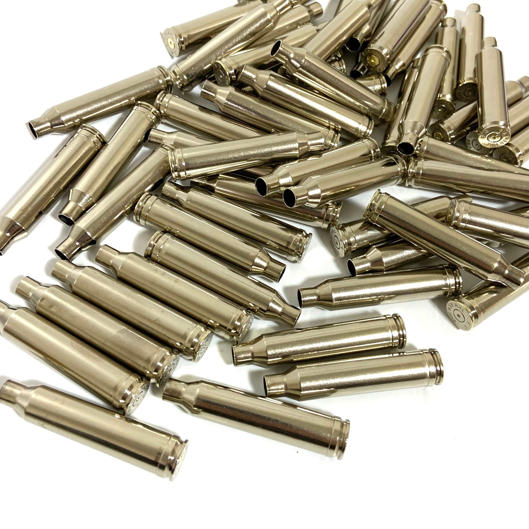 A loose pile of empty nickel-plated 7mm Remington Magnum rifle shell casings for reloading.
