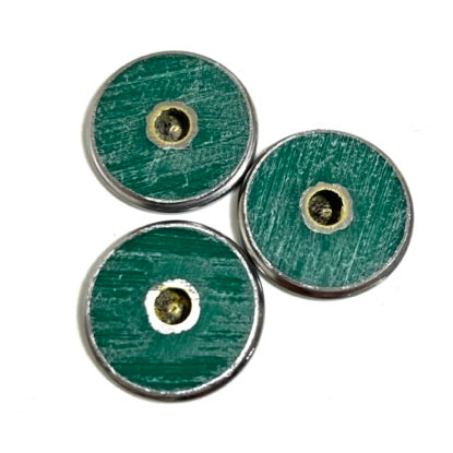Three Remington 12 gauge bullet slices shown from the back, green hull material with a drilled hole through the center and brass ring visible