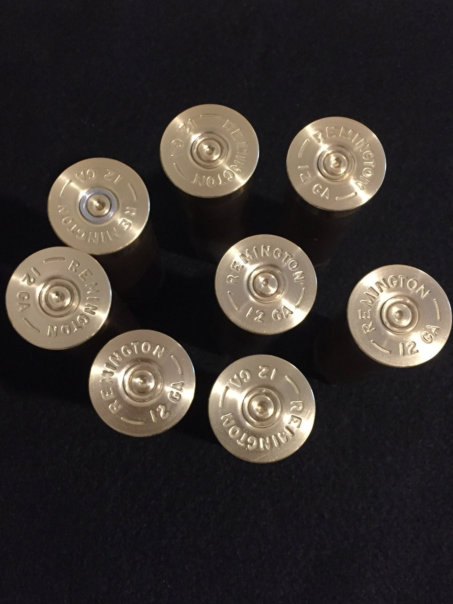 Eight gold 12 gauge headstamps arranged in a circle on dark background with readable Remington 12 GA text.