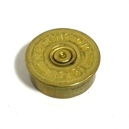 A single Remington B\brass gold 12ga brass headstamp on white background displayed at an angle showing stamped bottom base and rim wall