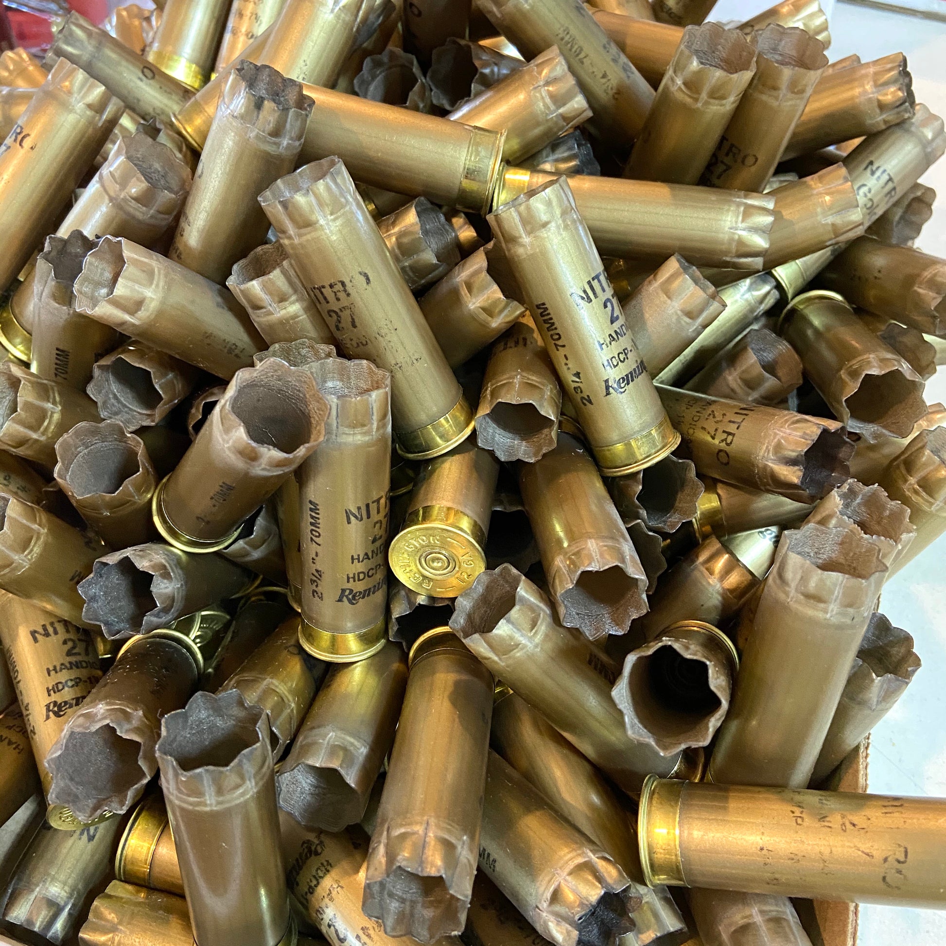 A large collection of spent gold shotgun hulls piled together for DIY crafts.