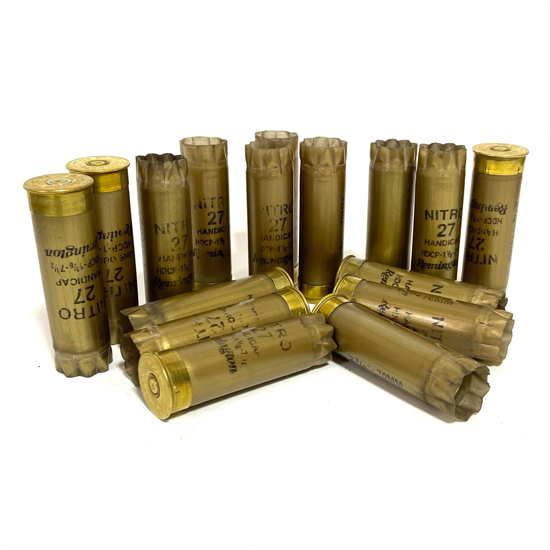 A cluster of gold Remington Nitro 27 shotshells wiped clean standing and lying on a white surface.