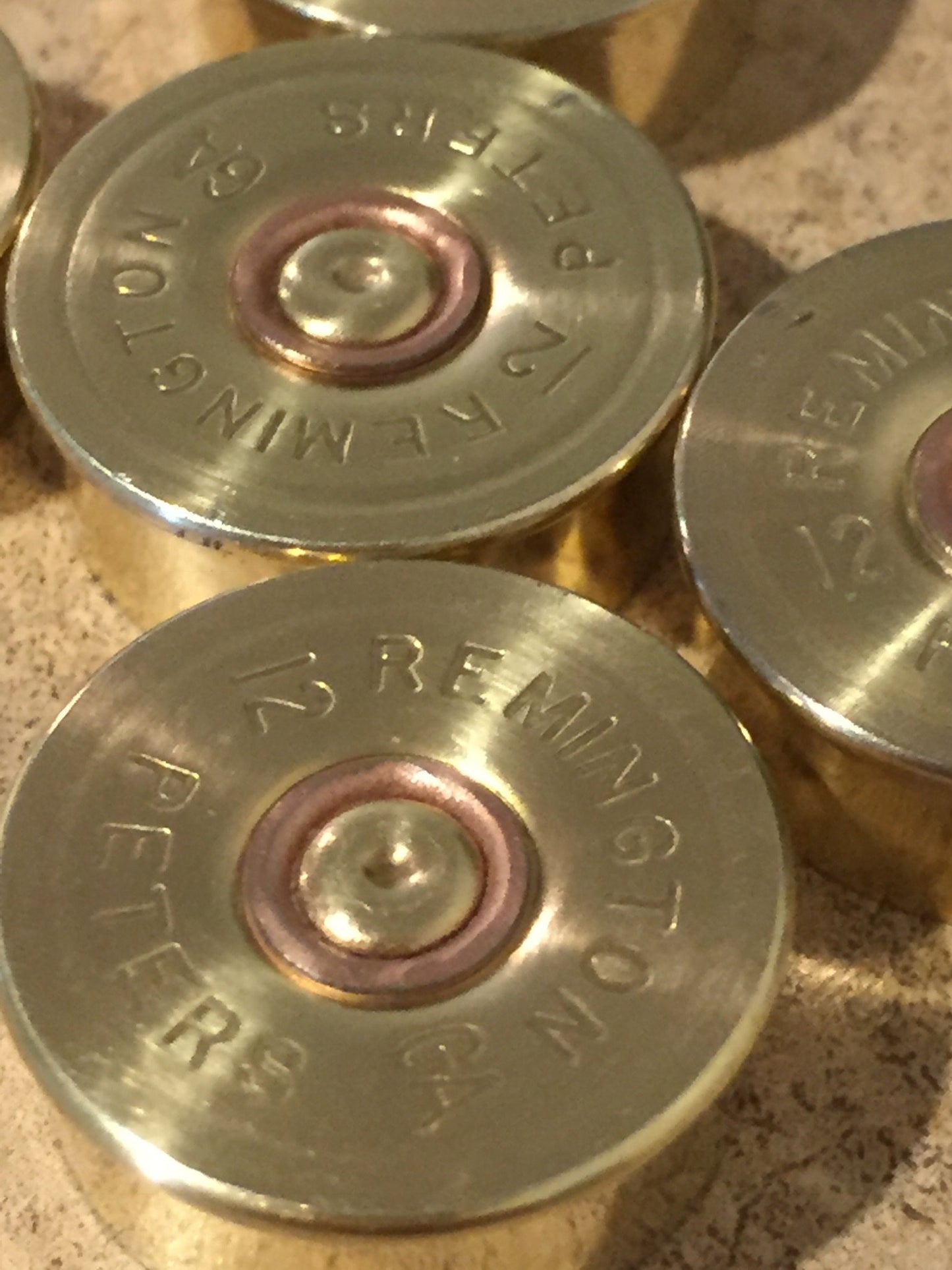 Closeup of gold-toned Remington Peters 12 gauge shotgun shell headstamps stacked together