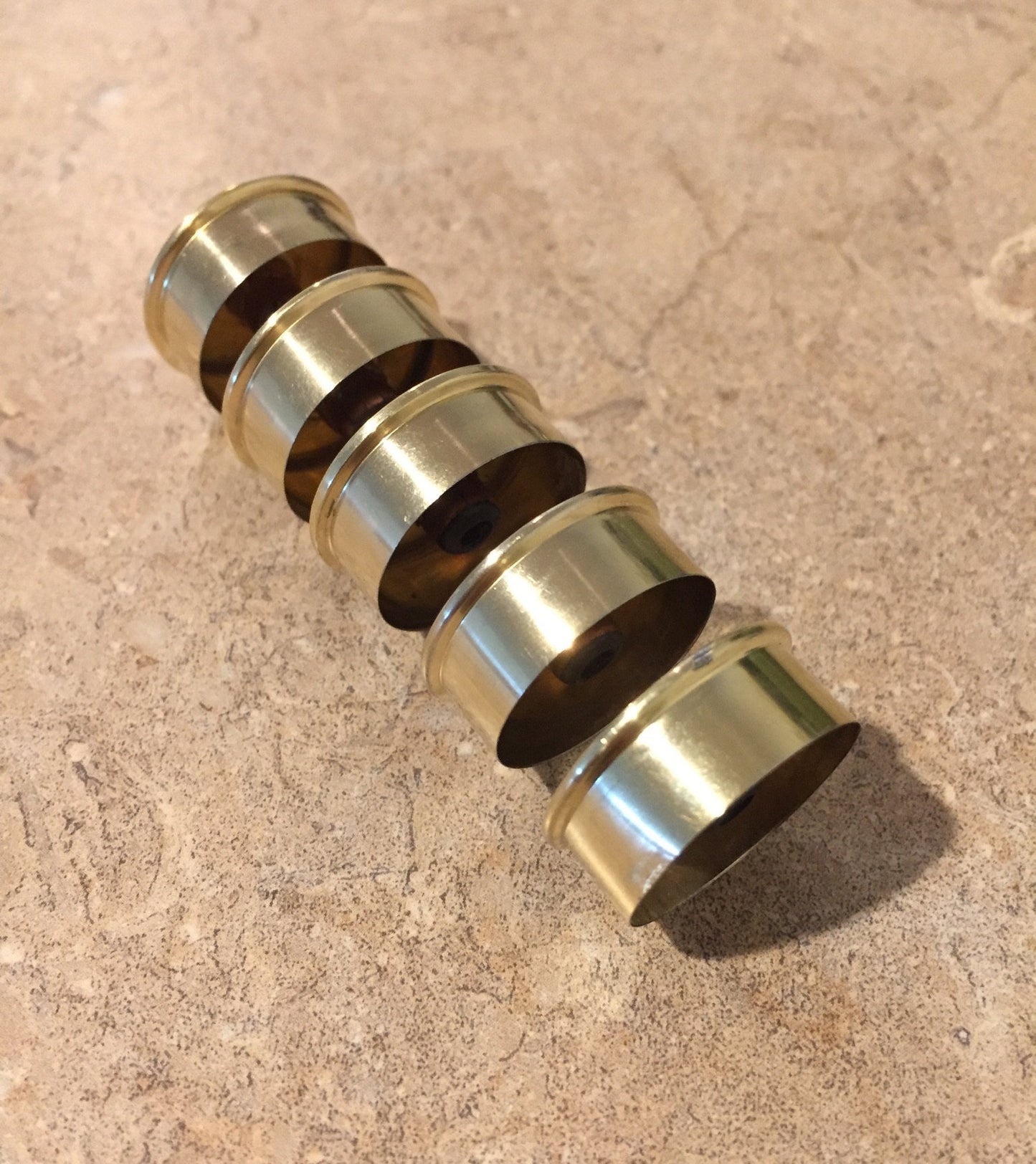 Row of gold-toned Remington Peters shotgun shell hulls stacked and nested together at an angle
