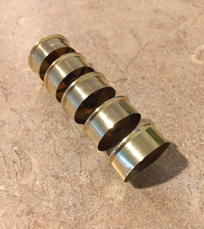 Row of gold-toned Remington Peters shotgun shell hulls stacked and nested together at an angle