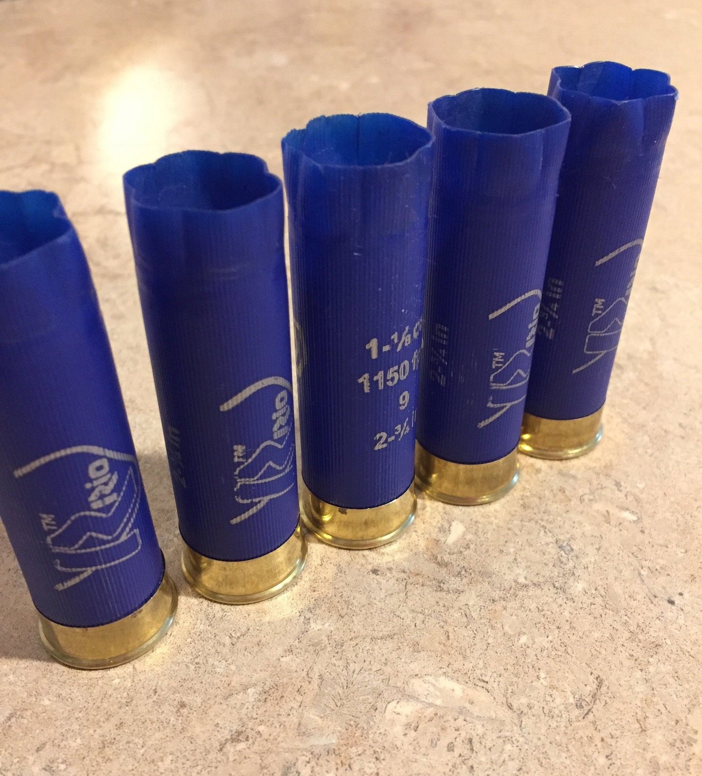 Five blue RIO 12ga empty shotgun casings lined up vertically 6 star crimp for display as crafting materials