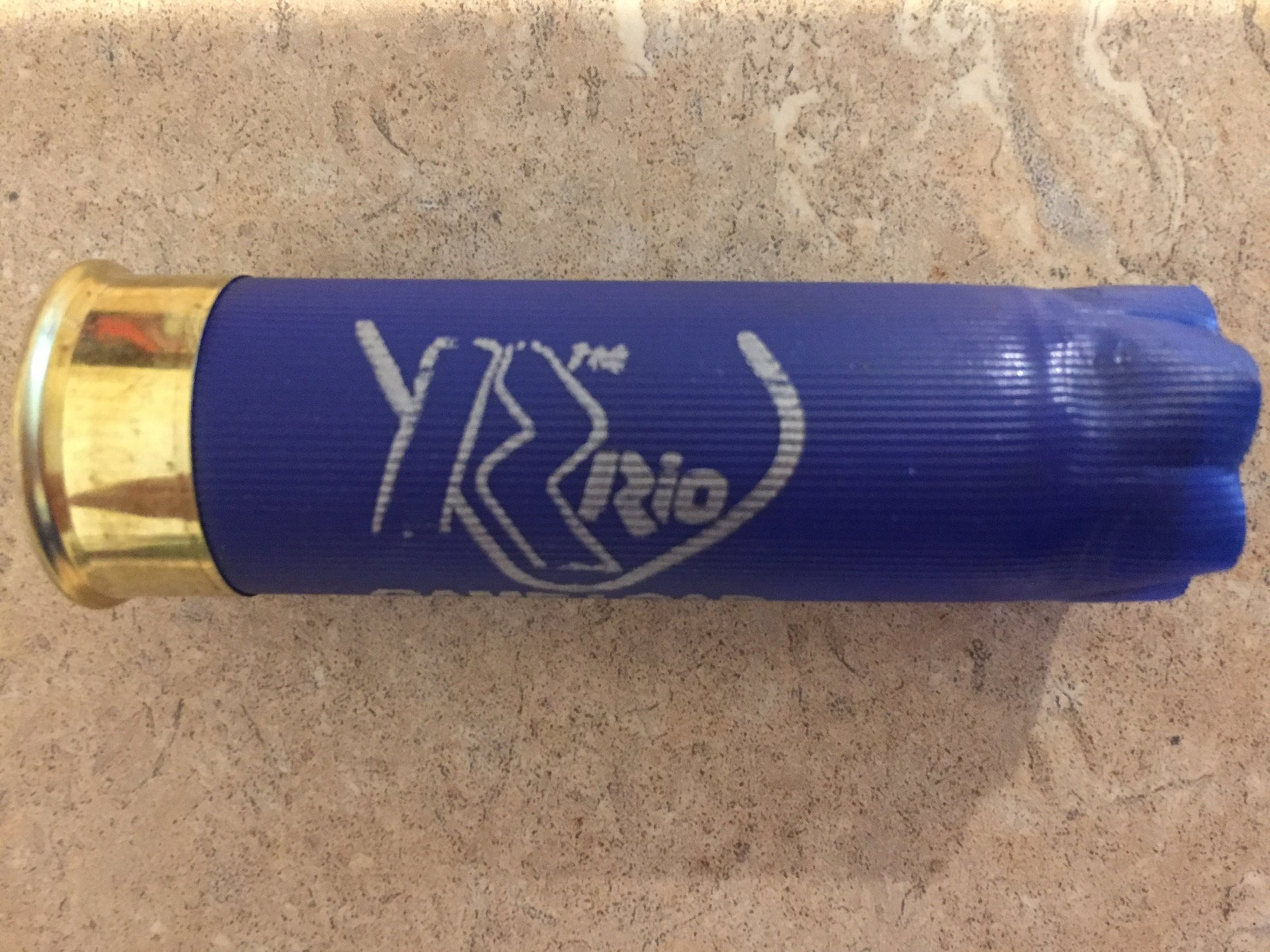 Close up of a single blue RIO 12ga spent shotgun hull with gold-colored brass base