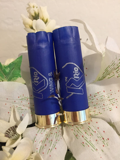 Two blue Rio 12 gauge shotgun shell hulls standing among white decorative flowers