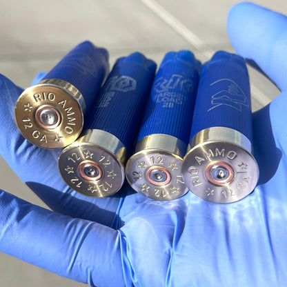Four blue Rio 12 gauge shotgun shell hulls held in a gloved hand showing brass "RIO Ammo 12 GA" headstamps