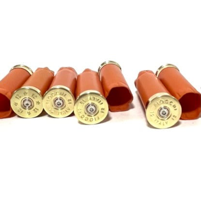 Horizontal row of blank orange 12 gauge shotgun shell casings for rustic wedding decor ammo.
