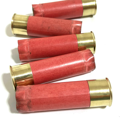 5 salmon pink paper shotgun shells with gold brass heads lying on a white background