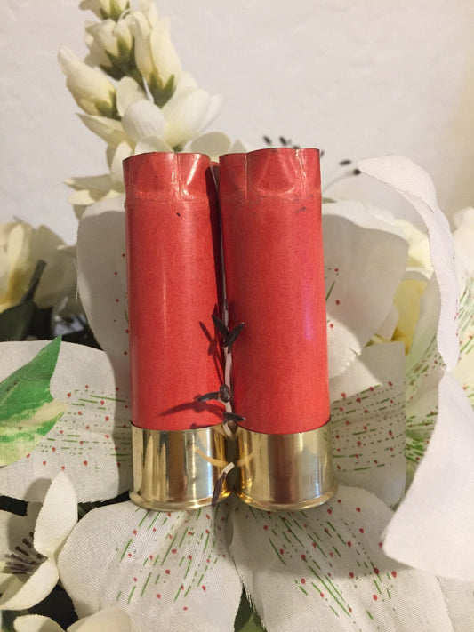 Two salmon pink paper shotgun shells with gold brass heads standing among white flowers