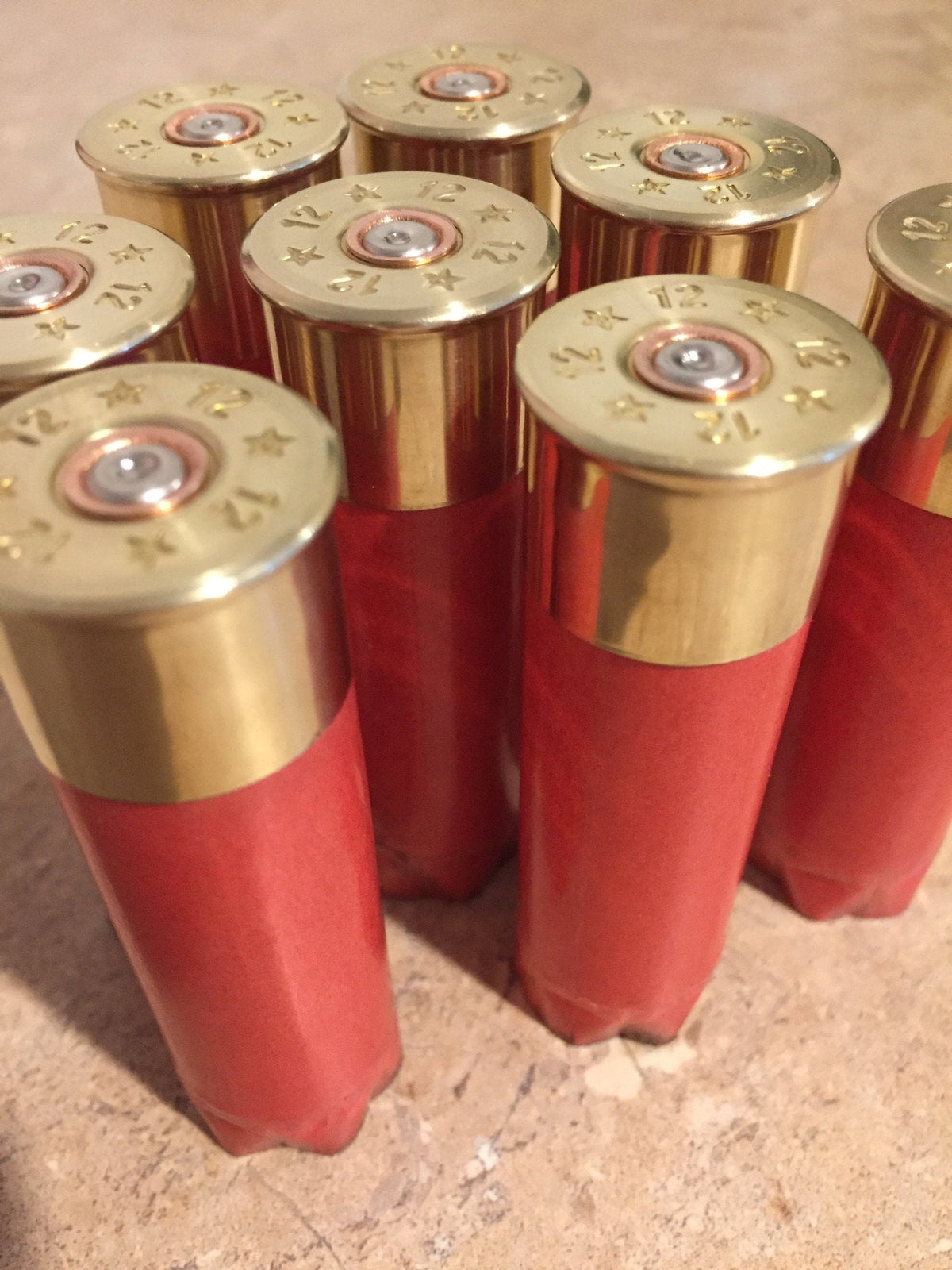 7 salmon pink Fiocchi 12 gauge paper shotgun shells standing with gold brass heads on a stone surface