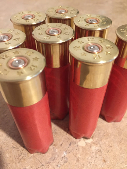 7 salmon pink Fiocchi 12 gauge paper shotgun shells standing with gold brass heads on a stone surface