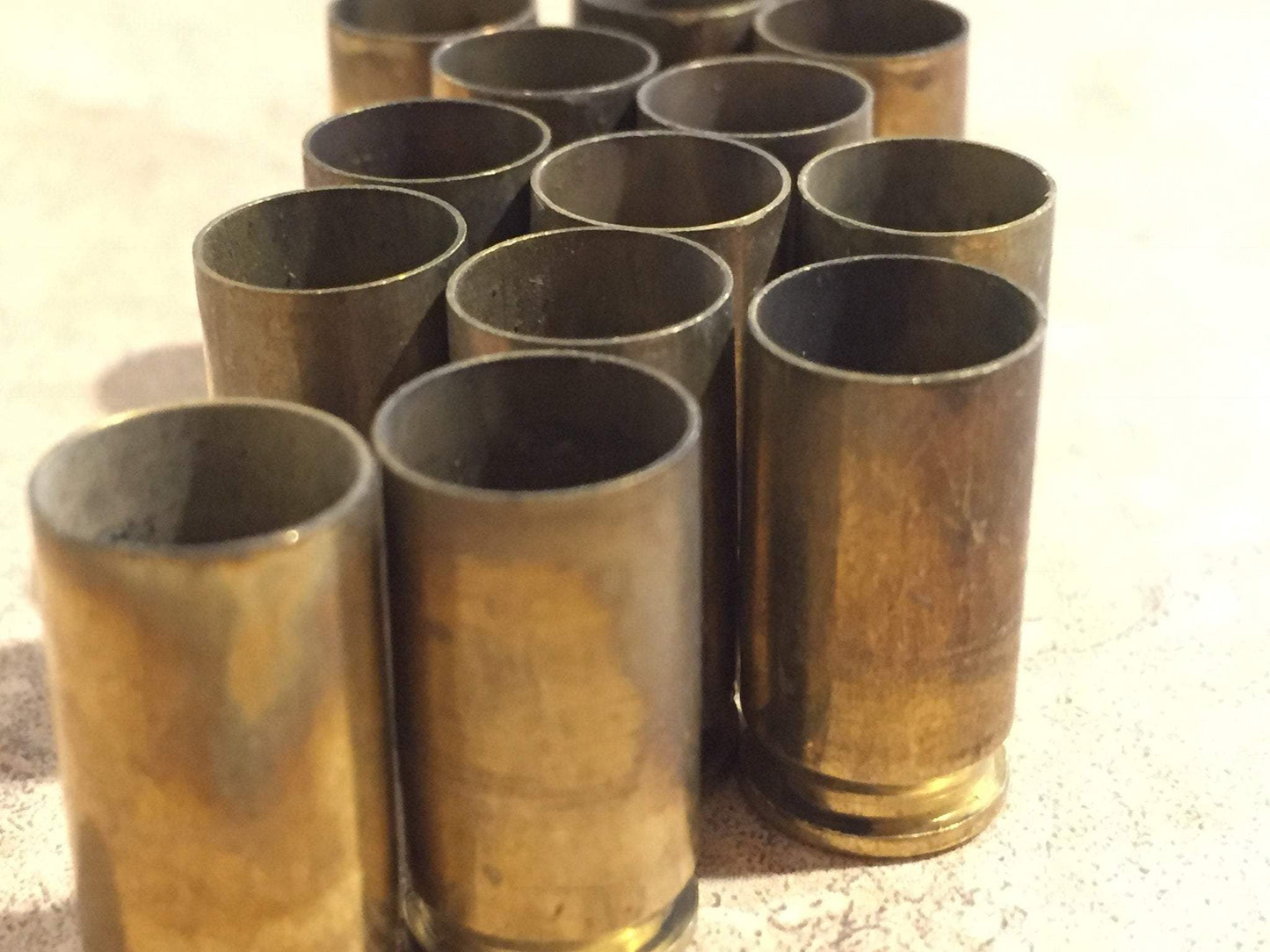 Cluster of brass shells standing upright, mouths open, on a light surface
