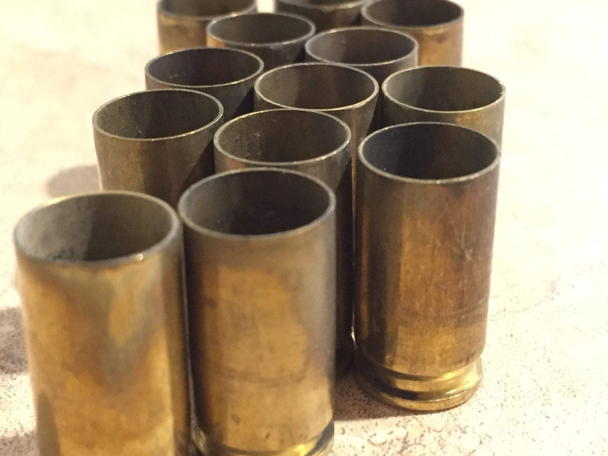 Cluster of brass shells standing upright, mouths open, on a light surface