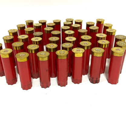 Group of red shotgun hulls used standing upside down showing brass primer bases facing up
