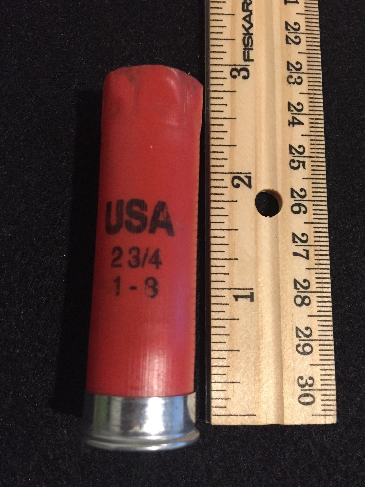A red Winchester USA shotgun shell beside a ruler showing a length of about 2.75 inches