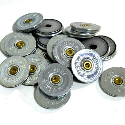 Pile of silver 12 gauge shotgun shell slices stamped USA showing gold primers