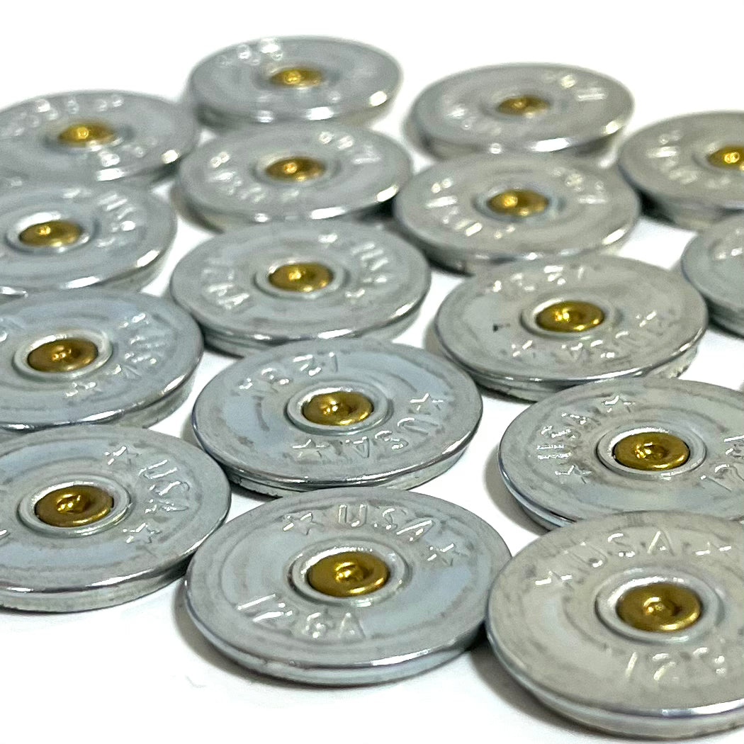 Close-up of silver 12 gauge shotgun shell slices stamped USA arranged in overlapping rows showing gold primers