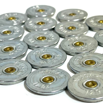 Close-up of silver 12 gauge shotgun shell slices stamped USA arranged in overlapping rows showing gold primers