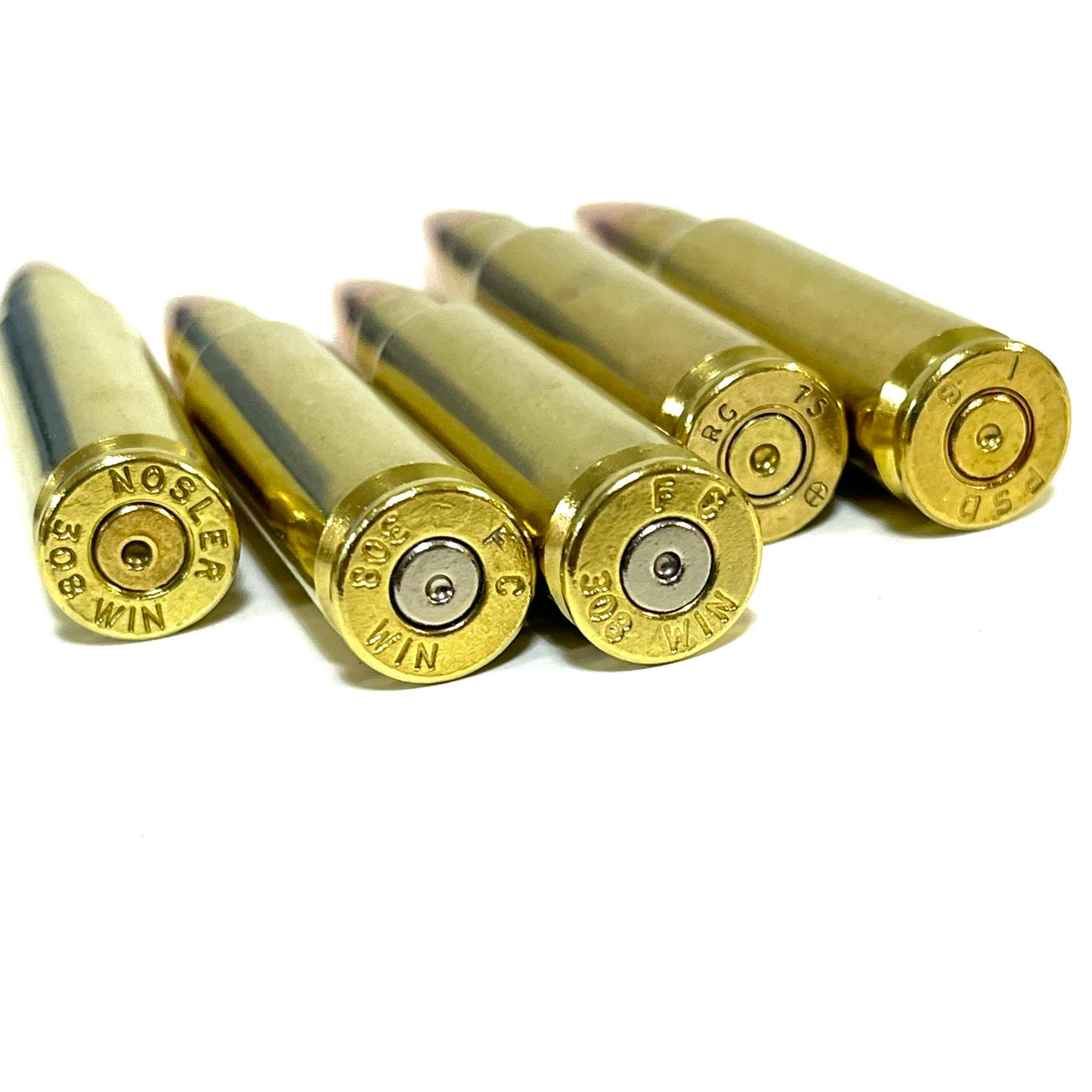 Five brass .308 snap cap props angled to show spent primers and headstamps, including a NOSLER 308 WIN marking