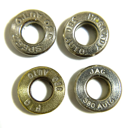 Four 380 Auto bullet slices on white with readable Speer, Hornady, R-P, and JAG headstamps and deprimed open holes.
