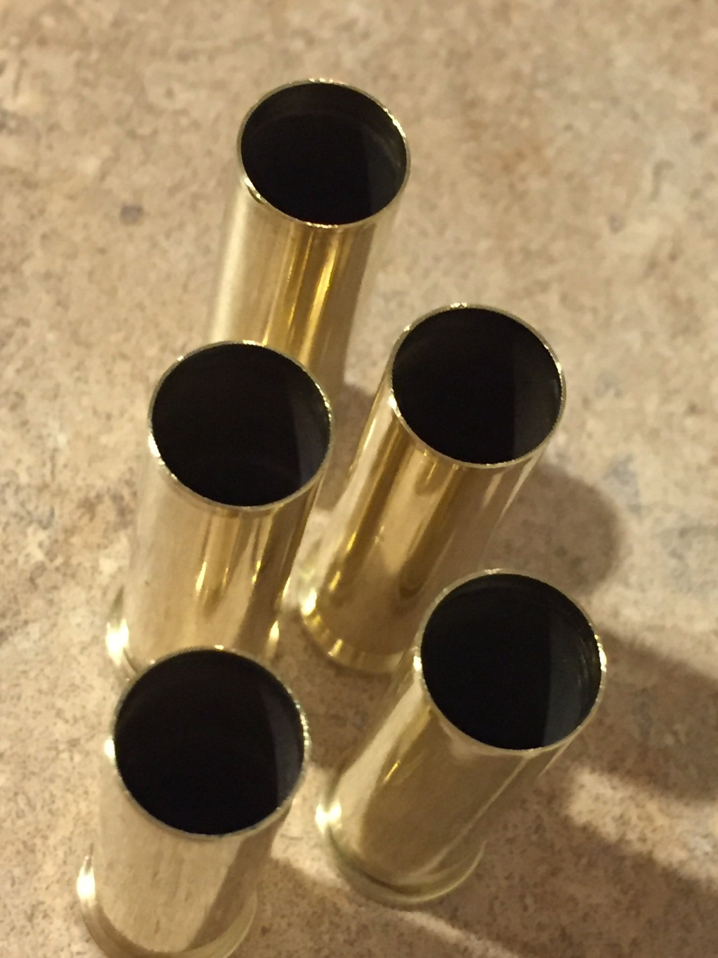 Top-down view of five polished 357 Magnum spent brass shells standing upright, showing dark open top mouths.
