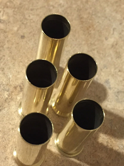 Top-down view of five polished 357 Magnum spent brass shells standing upright, showing dark open top mouths.