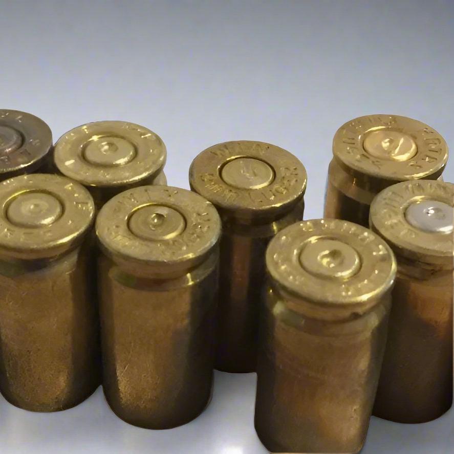 Seven spent 9mm brass casings standing upright together displaying stamped bases and indented primers.