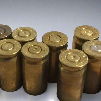 Seven spent 9mm brass casings standing upright together displaying stamped bases and indented primers.