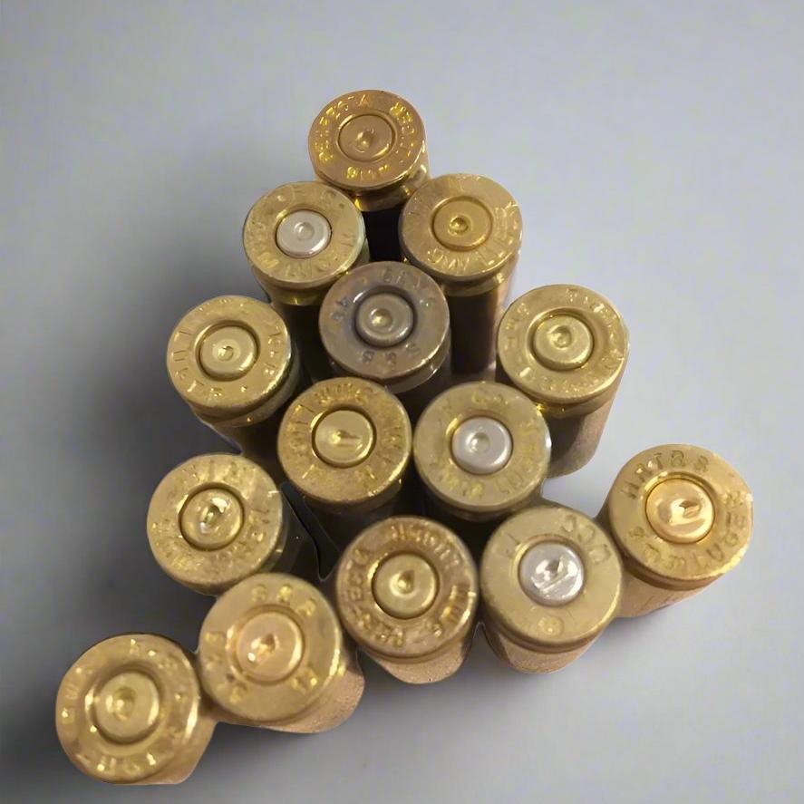 Thirteen spent 9mm casing bases standing upright displaying stamped headstamps and indented primers.