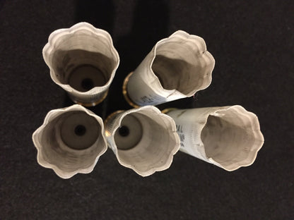 Top-down view of five white empty shotgun hulls showing the opened crimped tops.
