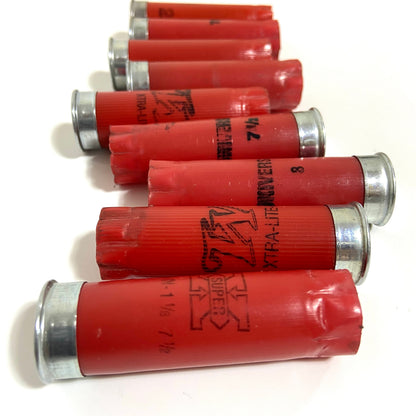 Five red 12 gauge spent shotshells with silver metal bases arranged in a horizontal stack on a white background.